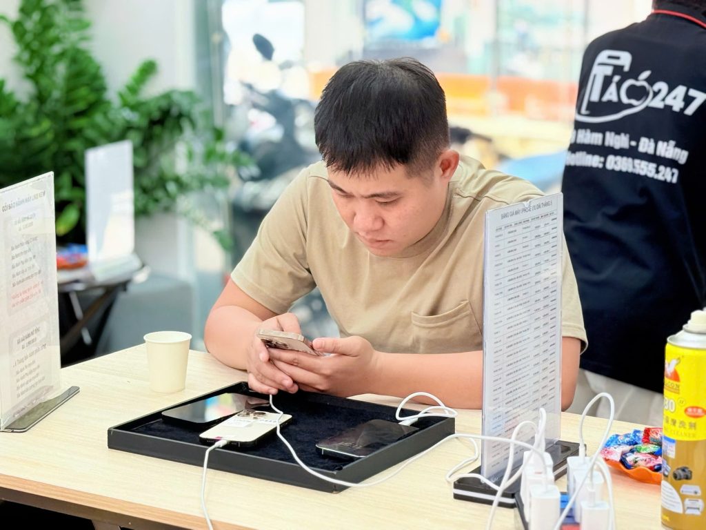 Khách hàng nam đang test iPhone 11 cũ tại cửa hàng Táo 247 Đà Nẵng – kiểm tra kỹ lưỡng trước khi mua
