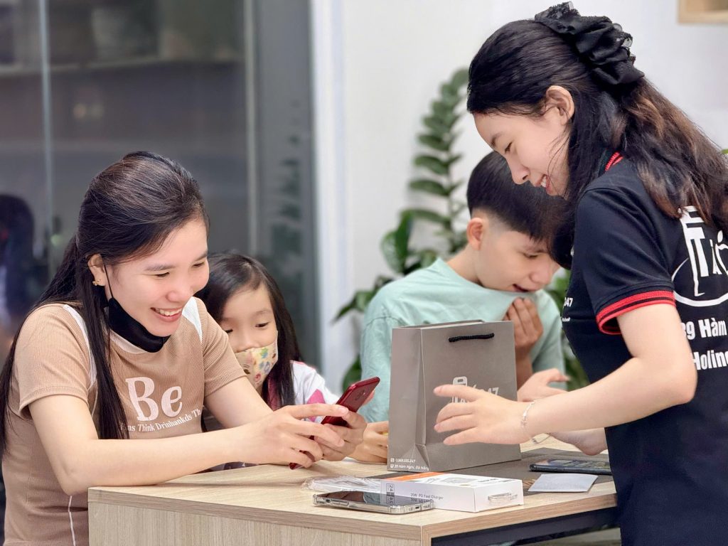 Khách hàng nữ nhận iPhone cũ Fullbox tại Táo 247 Đà Nẵng cùng gia đình
