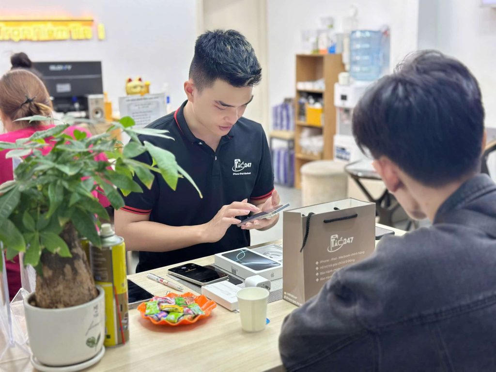 Nhân viên Táo 247 hỗ trợ khách hàng kiểm tra iPhone mới sau khi thu cũ đổi mới tại Đà Nẵng