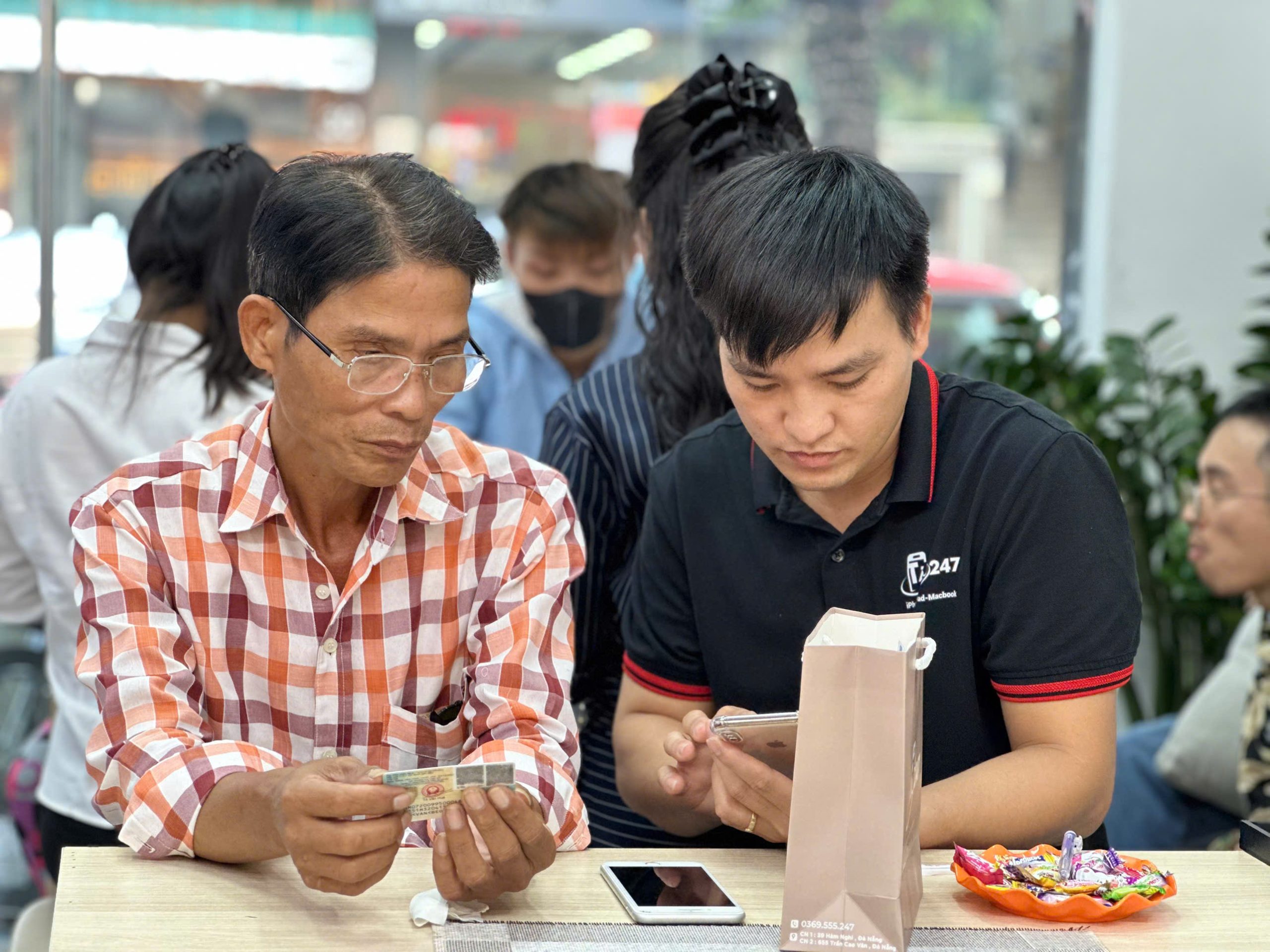 Nhân viên Táo 247 hướng dẫn khách hàng lớn tuổi làm thủ tục mua iPhone trả góp không cần trả trước